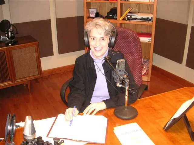 Nancy DeMoss Wolgemuth recording in a studio, wearing headphones and writing notes beside a microphone.